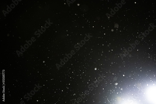Snow and bokeh in the light of a lantern on a black background