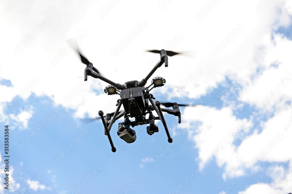 Quadcopter flying in the blue, cloudy sky Quadcopter flying in the blue, cloudy sky