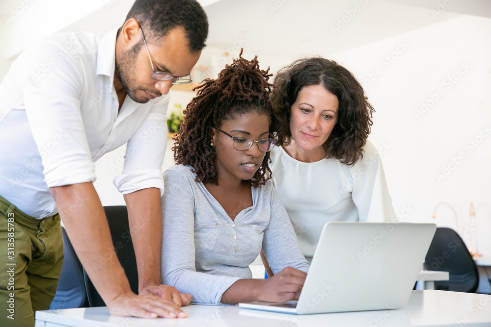 Confident employees talking while working with laptop. Thoughtful workers discussing some work issues. Technology concept Confident employees talking while working with laptop. Thoughtful workers discussing some work issues. Technology concept
