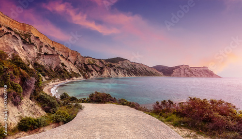 Colorful sunset on the beach on the greek island. Nature in twilight period which including of sunrise over the sea and the nice beach. Summer beach with blue water and purple sky at the sunrise.