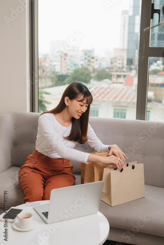 Young asian female with shopping bags in living room.