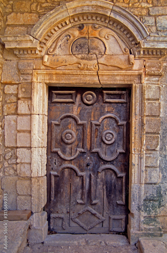 An old decorated wooden door with surrounding decorative classical stonework in Provence South of France An old decorated wooden door with surrounding decorative classical stonework in Provence South of France