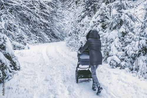 Mother with pram in winter forest photo