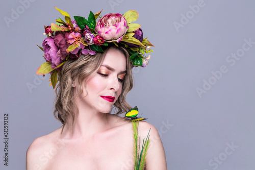 tender young woman posing in flower wreath with artificial  greenbutterfly,  isolated on grey photo