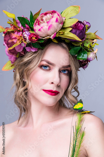 tender young woman  posing in flower wreath with artificial  greenbutterfly,  isolated on grey photo