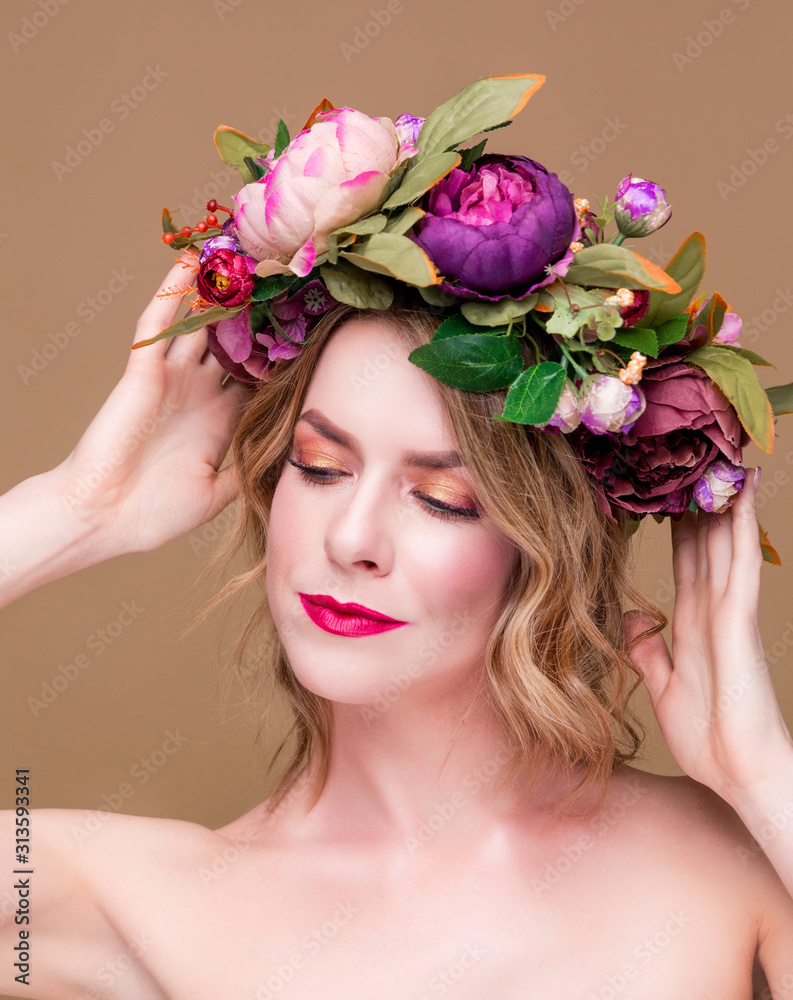 beautiful young woman model with bright flowers on her head on the ocher color background beautiful young woman model with bright flowers on her head on the ocher color background