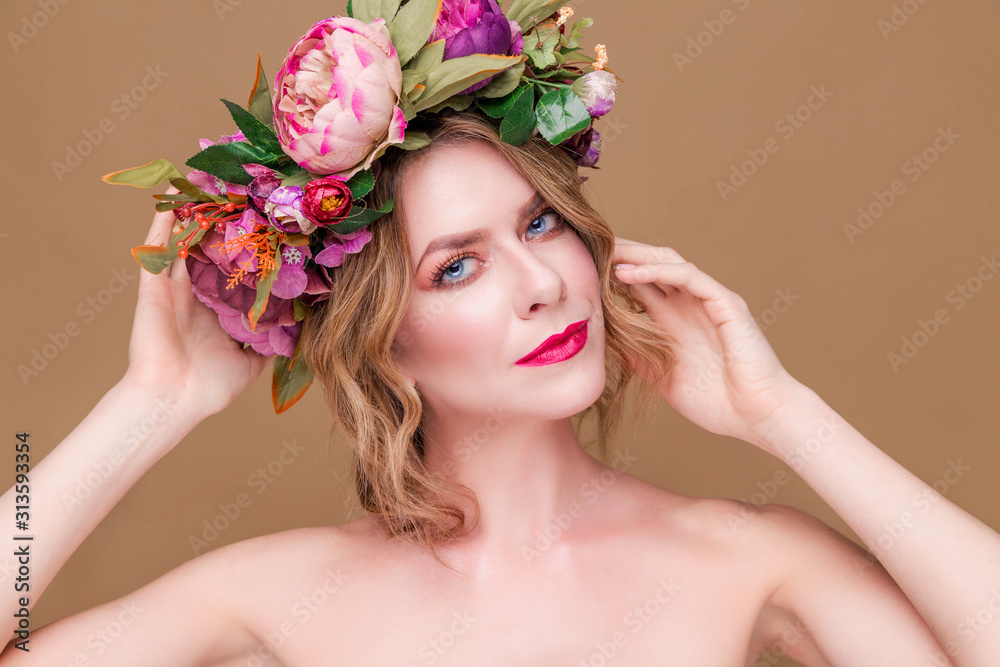 beautiful young woman model with bright flowers on her head on the ocher color background beautiful young woman model with bright flowers on her head on the ocher color background