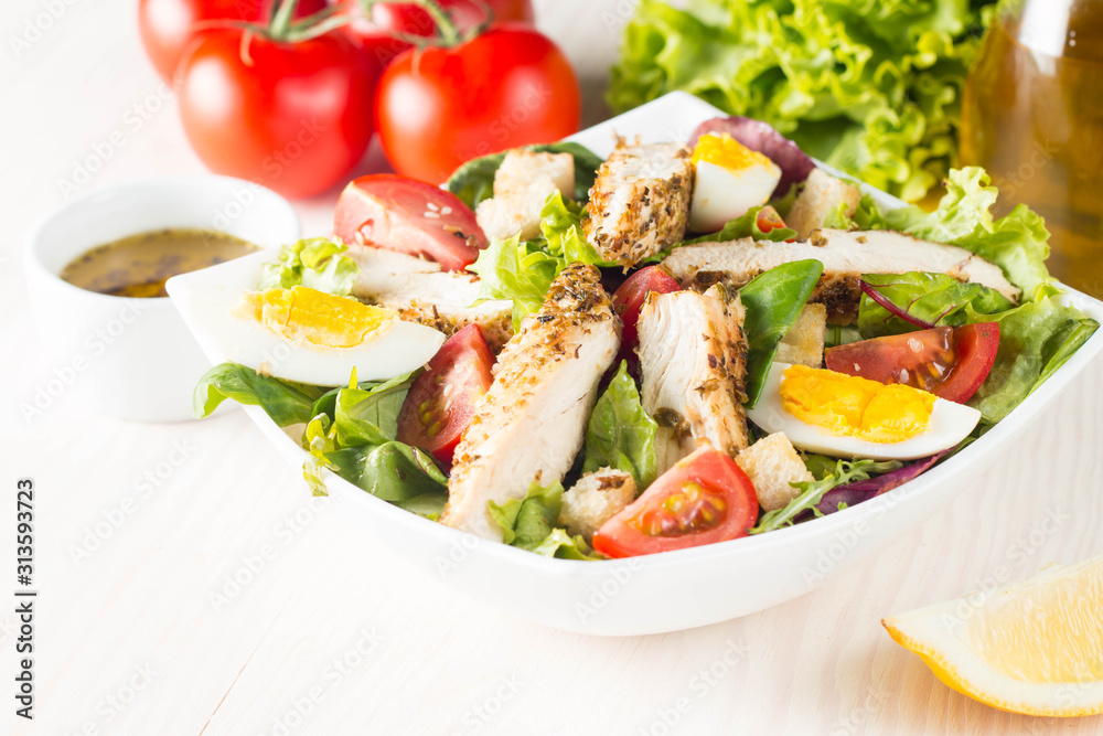Fresh Caesar salad with delicious chicken breast, ruccola, spinach, cabbage, arugula, egg, parmesan and cherry tomato on wooden background. Oil, salt and pepper. Healthy and diet food concept. Fresh Caesar salad with delicious chicken breast, ruccola, spinach, cabbage, arugula, egg, parmesan and cherry tomato on wooden background. Oil, salt and pepper. Healthy and diet food concept.