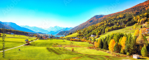 Magnificent autumn view of St.Valentin village and Haidersee (Lago della Muta) lake with Ortler peak on background.
