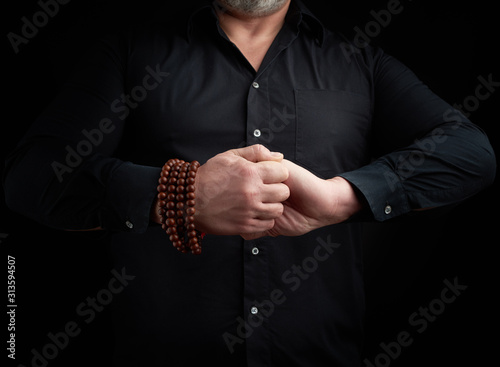 man in a black shirt crossed his arms in front of the torso, performing mudra
