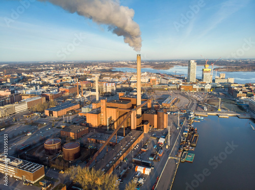 The factory chimney smokes in the city. Aerial drone view.