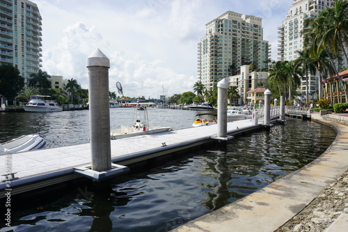 An image of Fort Lauderdale, florida overlooking the river with a dock and boats with some buildings in the background