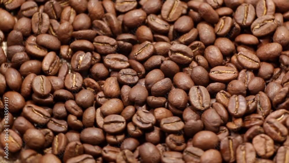 Fragrant coffee beans scrolls slowly around the camera. Coffee beans roasted rotating blurry background close up. Fragrant coffee beans scrolls slowly around the camera. Coffee beans roasted rotating blurry background close up.