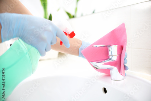 A woman in gloves cleans the bathroom.