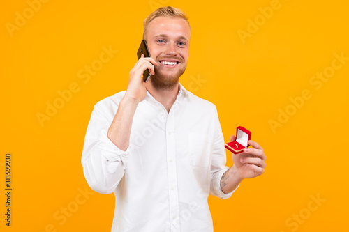Fotografie young groom in a white shirt makes a marriage proposal to the bride holding a ri