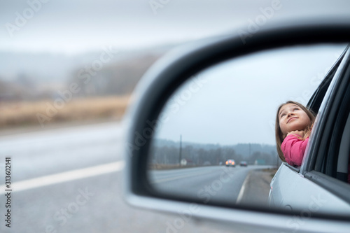 Young girl ride car and look out open window. Trip and responsible travel concept Teenager lifestyle. Childhood memories. Family time and road trip. Stock photo.