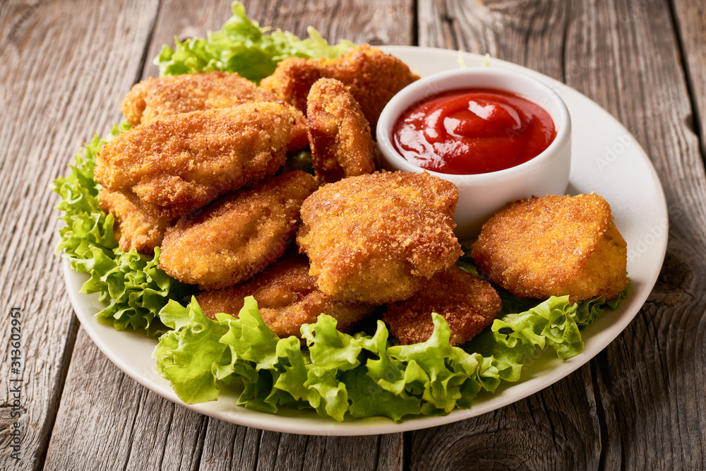 Close up plate with fried chicken nuggets with lettuce and ketchup Close up plate with fried chicken nuggets with lettuce and ketchup