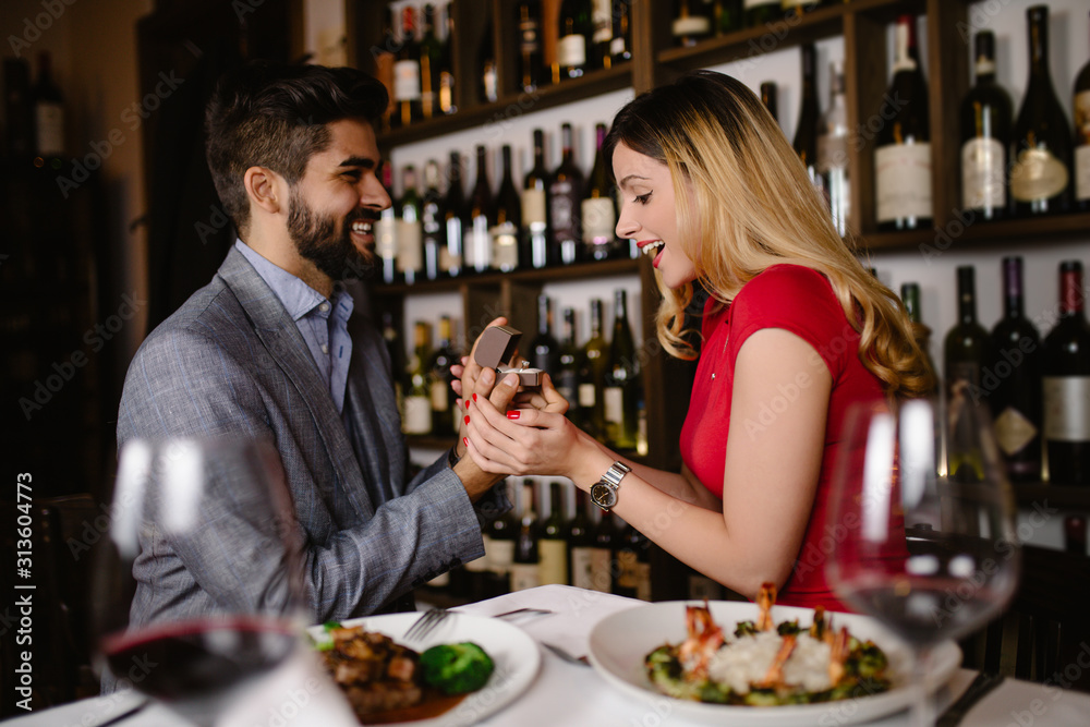 Handsome man proposing a beautiful woman to marry him in restaurant during date. Handsome man proposing a beautiful woman to marry him in restaurant during date.