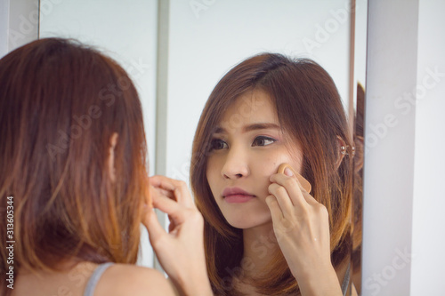 Portrait beautiful asian girl applying powder puff foundation at mirror in bedroom.