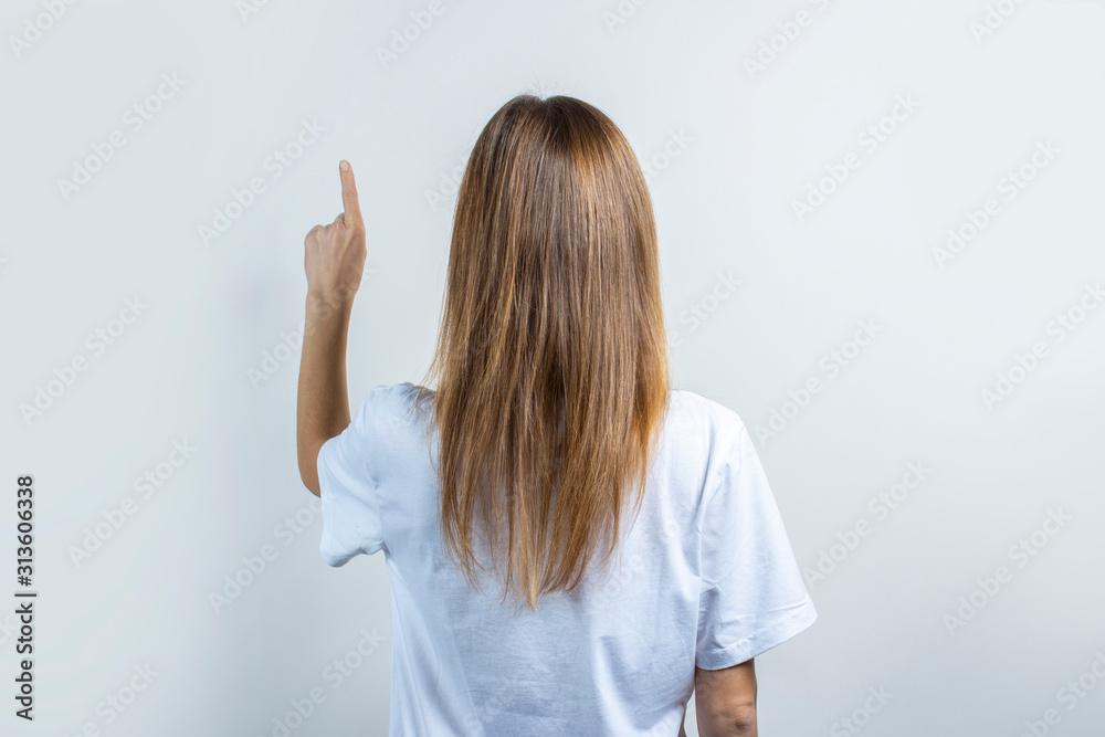 Young woman touches or pushes a finger at something on a light background Young woman touches or pushes a finger at something on a light background