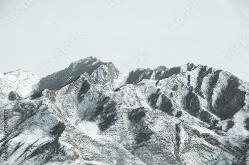 landscape of gray snow-capped mountains against a neutral sky, texture of winter mountains