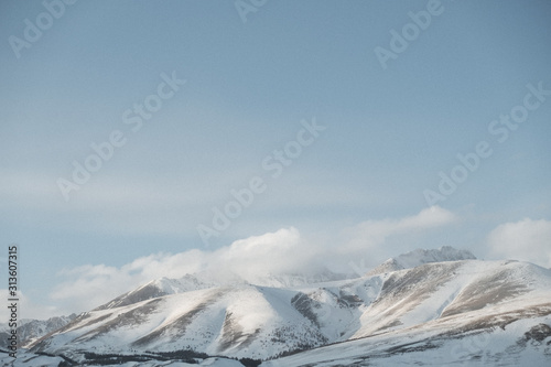 landscape of gray snow-capped mountains against a neutral sky, texture of winter mountains 