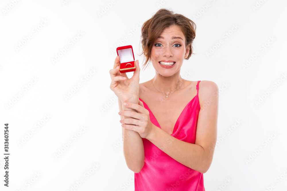 lovely girl with makeup in a pink dress shows a box with a ring on a white background lovely girl with makeup in a pink dress shows a box with a ring on a white background