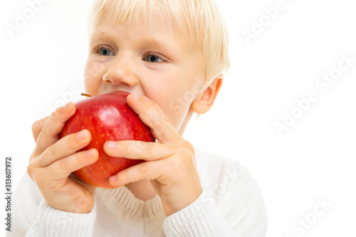 healthy eating concept. cool plan male child kid biting a ripe red apple on a white background with copy space