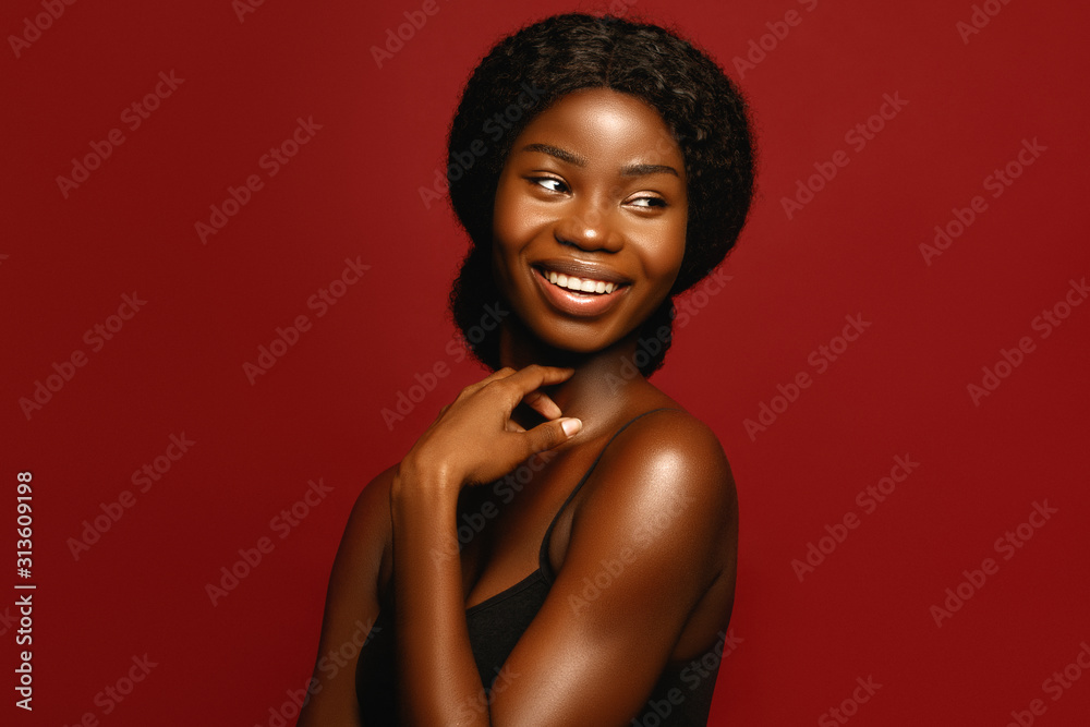 Beauty. African American beautiful woman portrait. Brunette curly haired young model with dark skin and perfect smile against red background - obrazy, fototapety, plakaty 