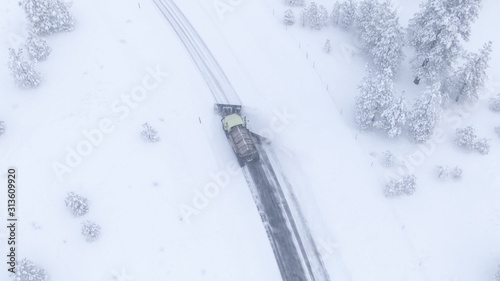 DRONE: Truck plowing and salting a road crossing the scenic wintry countryside.