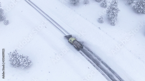 Fototapeta Naklejka Na Ścianę i Meble -  AERIAL: Flying above a snow plough truck clearing a snowy road in rural America.