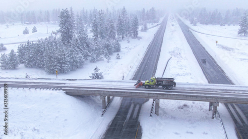 DRONE Truck plows a road crossing the interstate highway in wintry United States
