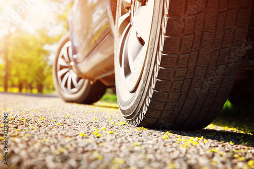 Fototapeta Naklejka Na Ścianę i Meble -  Car tires closeup on asphalt road on summer day at park