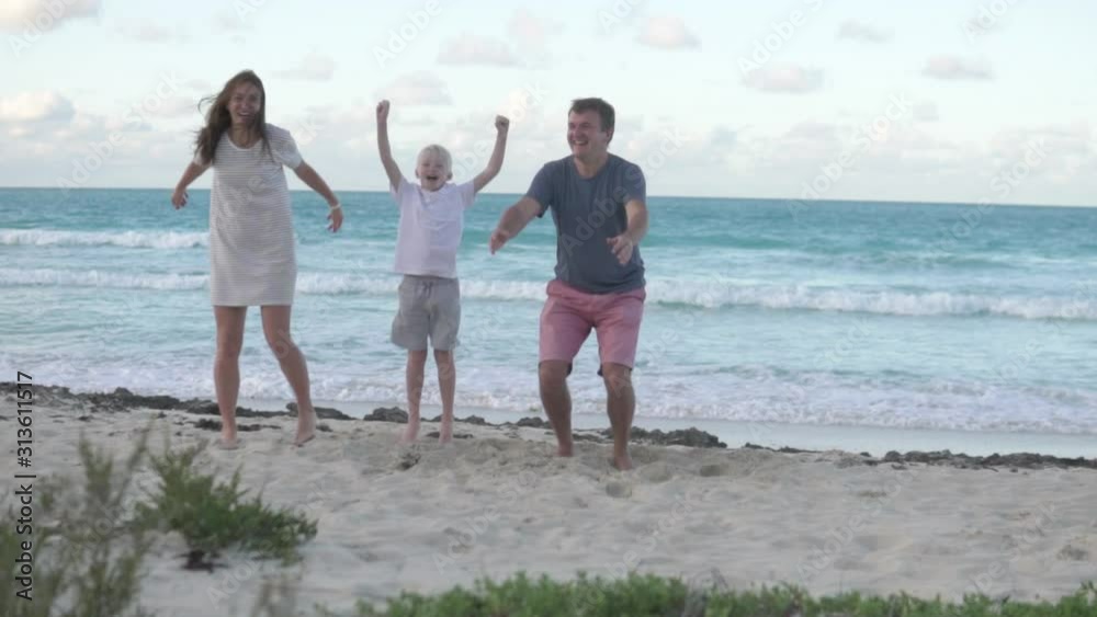 The family happily jumps up against the sea. Slow-motion, front view, The family happily jumps up against the sea. Slow-motion, front view,