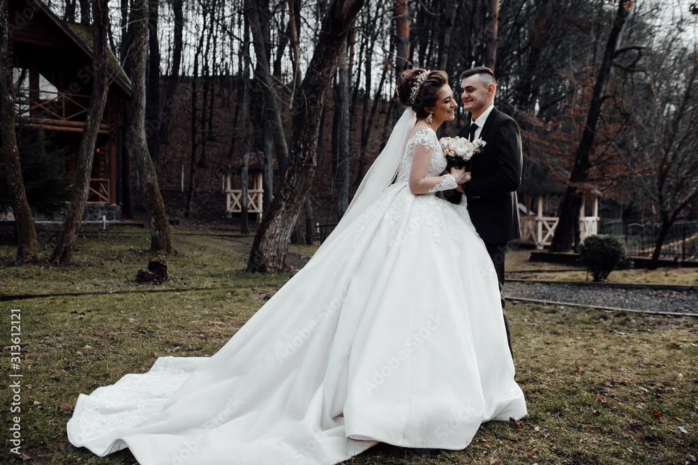 Happy to be together. Lovely wedding couple walking. Pretty bride and stylish groom celebrating their marriage. Happy just married young couple. Romantic couple newlyweds in the garden. 