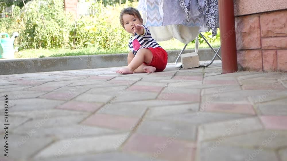 A small child crawls along the street. The baby learns to crawl. Sunny summer day for a child. Cognizes the world A small child crawls along the street. The baby learns to crawl. Sunny summer day for a child. Cognizes the world