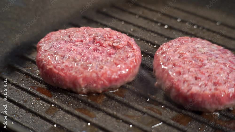 Two juicy cutlets of minced meat are fried on the grill in oil Two juicy cutlets of minced meat are fried on the grill in oil