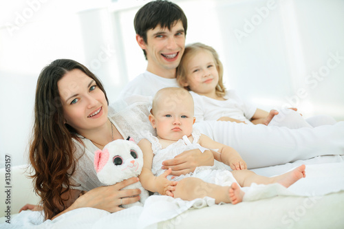 friendly young family lying on bed together