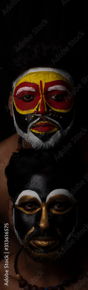 Indian brunette men with their faces painted by vibrant colors like a tribe standing in front of a black studio copy space background. Indian hi fashion. Indian brunette men with their faces painted by vibrant colors like a tribe standing in front of a black studio copy space background. Indian hi fashion.