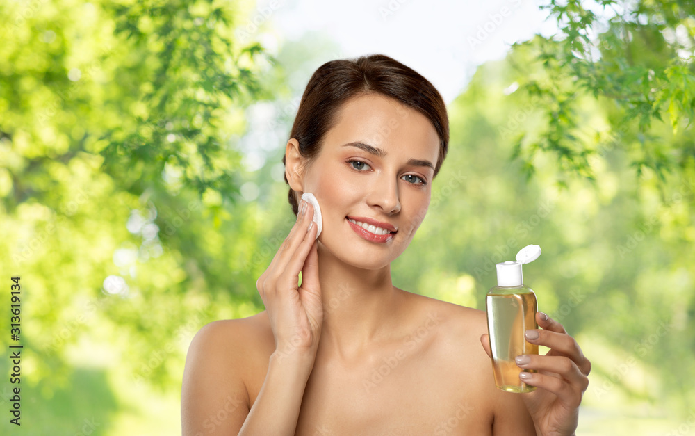 beauty, skin care and people concept - smiling young woman with toner or cleanser and cotton pad cleansing face over green natural background beauty, skin care and people concept - smiling young woman with toner or cleanser and cotton pad cleansing face over green natural background