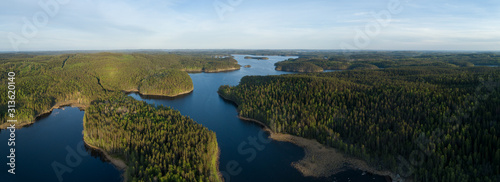 Aerial view of blue lake with island and green forests on a sunny summer day in Finland. Drone photography