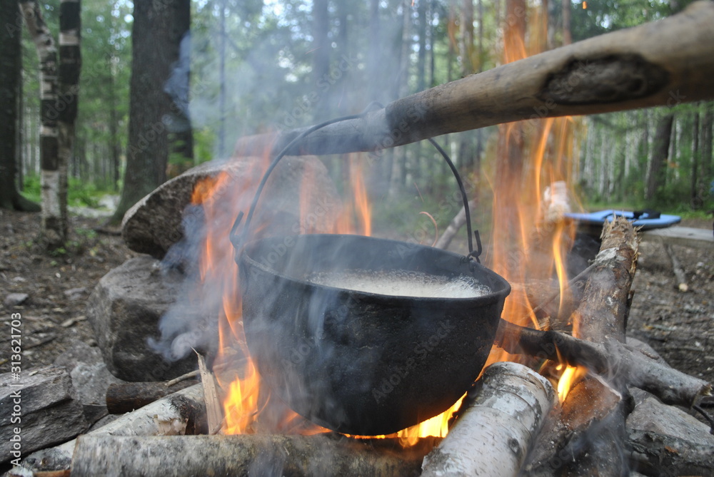 Cooking food in a cauldron that hangs over the fire and firewood, around the nature and camp of tourists. Cooking food in a cauldron that hangs over the fire and firewood, around the nature and camp of tourists.