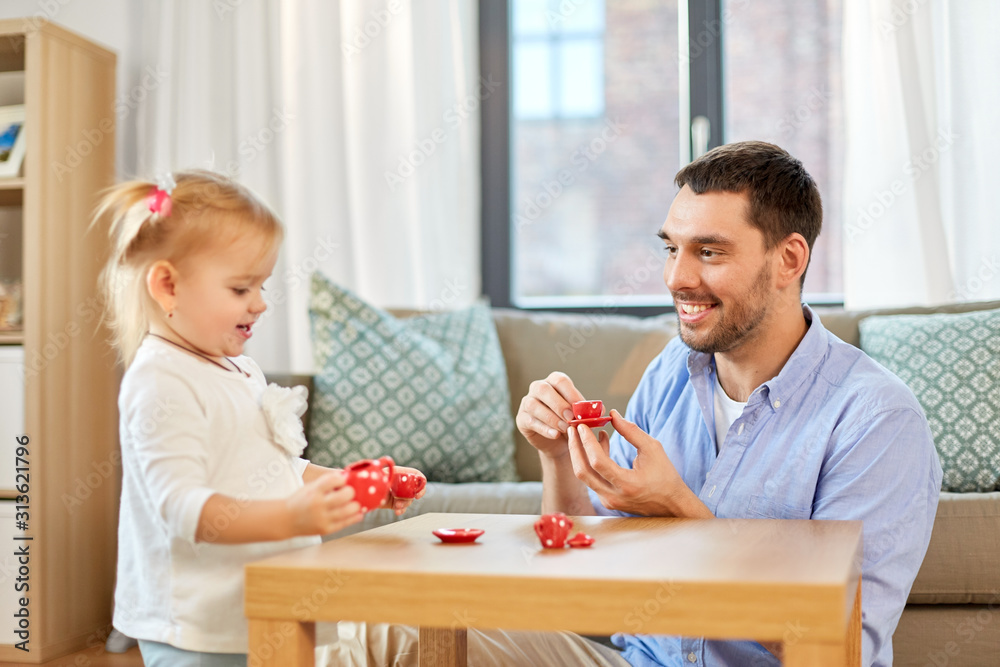 family, fatherhood and childhood concept - happy father and little daughter with toy crockery playing tea party at home family, fatherhood and childhood concept - happy father and little daughter with toy crockery playing tea party at home