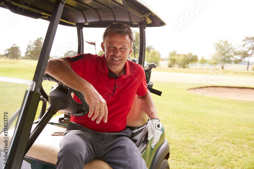 Portrait Of Mature Man Playing Golf Driving Buggy Along Course To Green On Red Letter Day