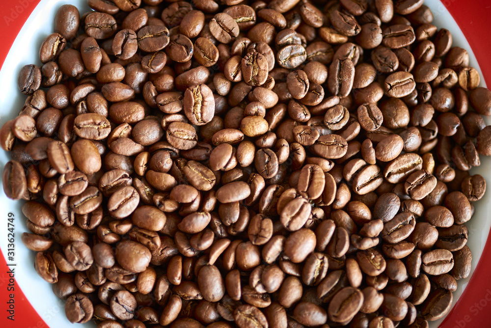 Fototapeta premium Nahaufnahmen von braunen Kaffeebohnen auf einem Teller mit roten Ecken