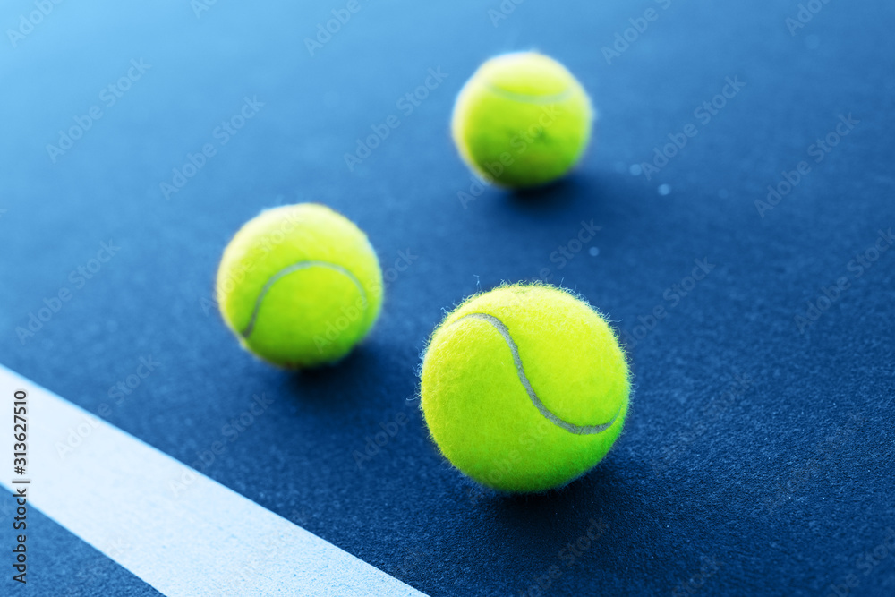 Tennis balls on a tennis court next to white line