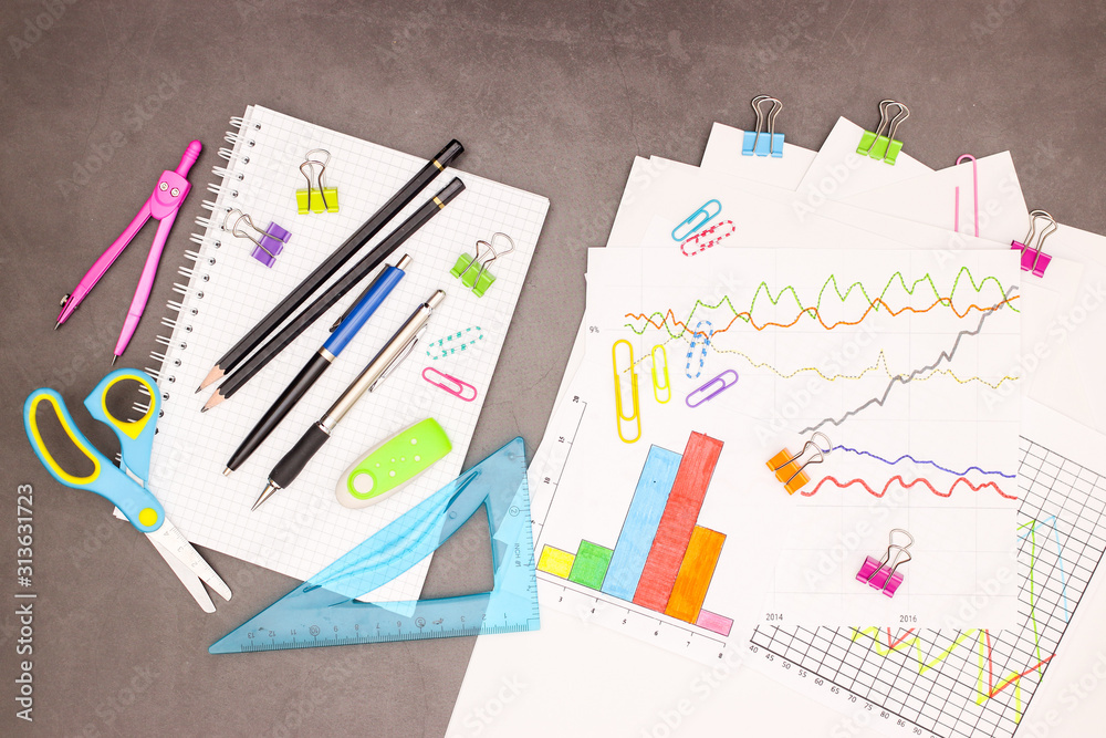 Lap top, statistics plans and office supplies on grey background Lap top, statistics plans and office supplies on grey background