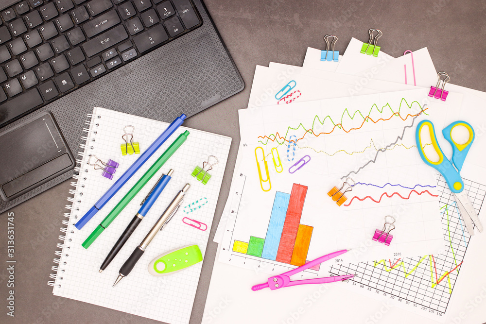 Lap top, statistics plans and office supplies on grey background Lap top, statistics plans and office supplies on grey background