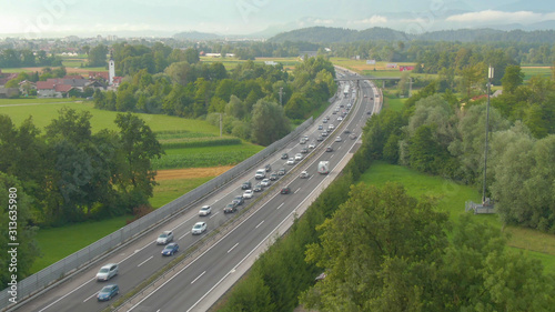 DRONE: Flying along long traffic jam formed on highway crossing the countryside