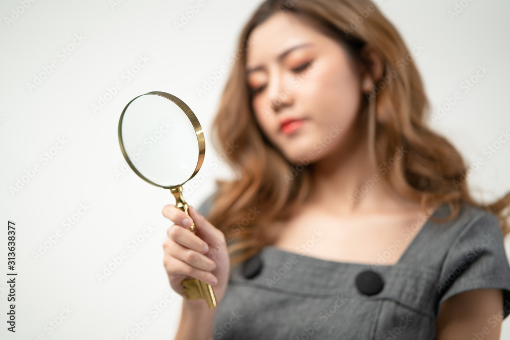 Portrait of beautiful Asian woman looks concentrate through magnifying glass selective focus, isolated on grey background with copy space, concept fashion detective, concentrate spy, seeking the truth Portrait of beautiful Asian woman looks concentrate through magnifying glass selective focus, isolated on grey background with copy space, concept fashion detective, concentrate spy, seeking the truth